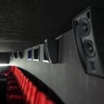 Sala de cinema com alto-falantes nas paredes e tela de projeção